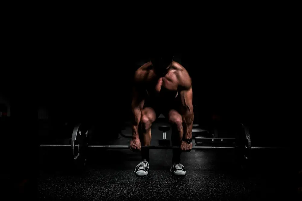 Shirtless man lifting barbell in gym, illustrating endurance and metabolic conditioning